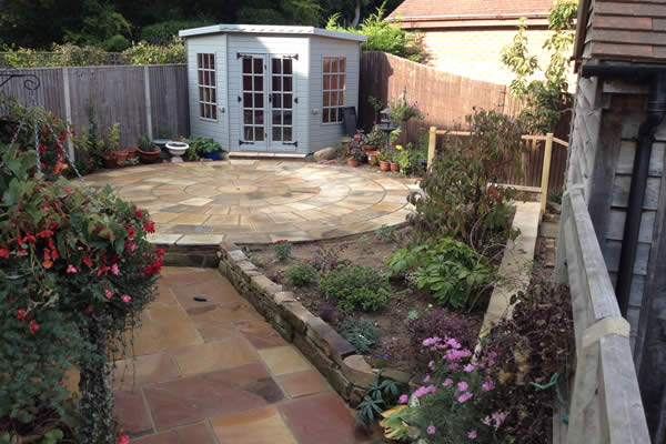 After: circular sandstone paving in front of a new summer house, with planted borders