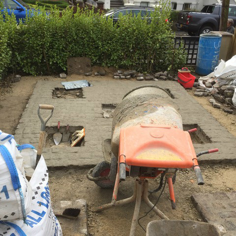 Paving being laid, with a cement mixer and tools on site